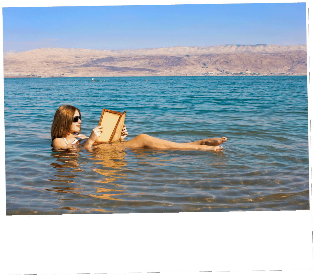 beautiful young woman reads a book floating in the waters of the Dead Sea in Israel